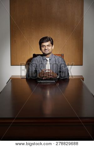 Positive Confident Entrepreneur Smiling At Camera When Sitting At Hie Big Office Table