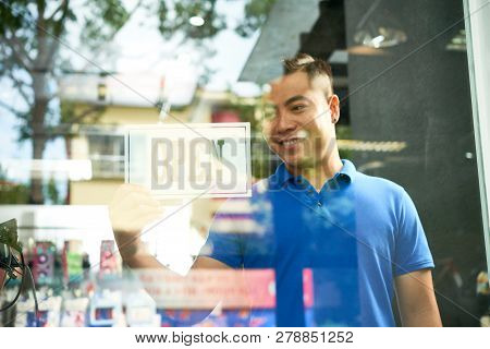 Smiling Vietnamse Shop Assistant Turning Open Sign On Store Door