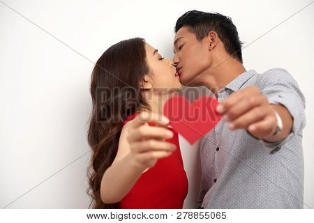 Young Asian Couple In Love Kising And Showing Red Paper Heart