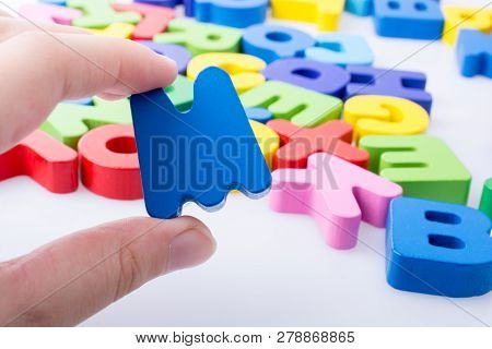 Letter M In Hand Beside Colorful Alphabet Letter Blocks Scattered Randomly