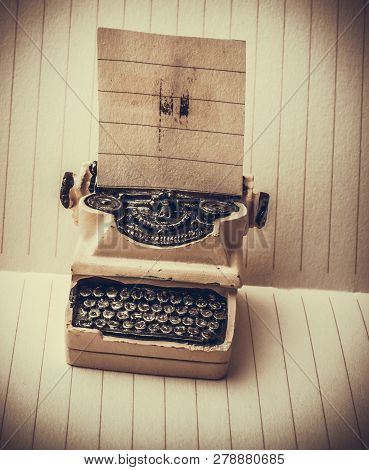 Retro Syled Tiny Typewriter Model On A Paper Background