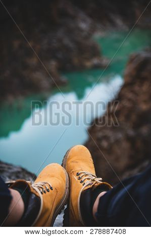 Feet Of Traveler In Boots Sitting Over River Canyon