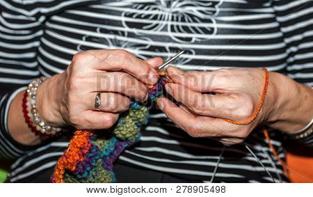 Hand Of Old Woman Holding Knitting Needles And Multi Colored Wool For Woolwork Of Warm Sweater For C