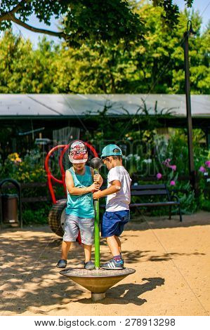 Poznan, Poland - July 29, 2018: Two Boys Playing On A Spinning Equipment At A Playground On A Sunny 