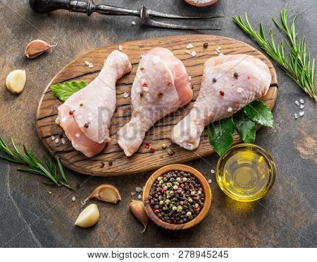Chicken legs with spices and salt  ready for cooking on cutting board.