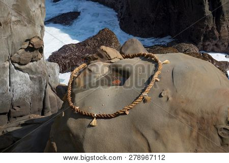Miyazaki, Japan - November 6, 2018: Target marked by a rope on a rock to throw small ceramic undama, or lucky balls in, at Udo Shrine to earn good luck
