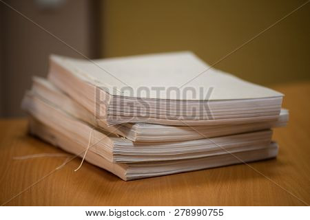 A Stack Of White Sheets Of Paper On The Office Desk