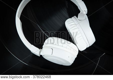White Wireless Headphones On Old Vinyl Records. Music Concept. Rretro Sound System