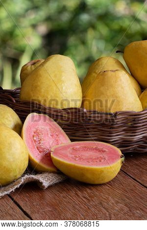 Photo Of Guava Fruit Cut In Basket On Wooden Background And Blurred Garden Background.