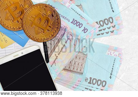 1000 Ukrainian Hryvnias Bills And Golden Bitcoins With Smartphone And Credit Cards. Cryptocurrency I