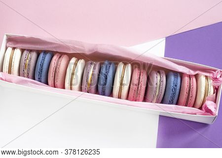 Multicolored Macarons In A White Box On A White, Pink, Violet Background