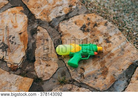 A Water Gun Lies On Wet Stones Near The Pool. Entertainment For Children And Adults. Water Games. A 