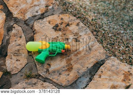 A Water Gun Lies On Wet Stones Near The Pool. Entertainment For Children And Adults. Water Games. A 
