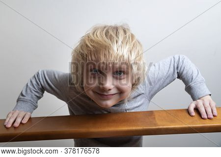 Boy With Blond Hair Looking Down From The Second Floor Of Bed