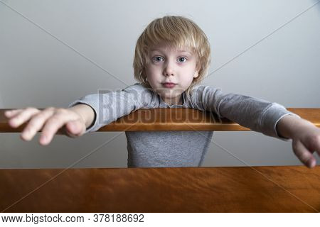 Boy With Blond Hair Looking Down From The Second Floor Of Bed