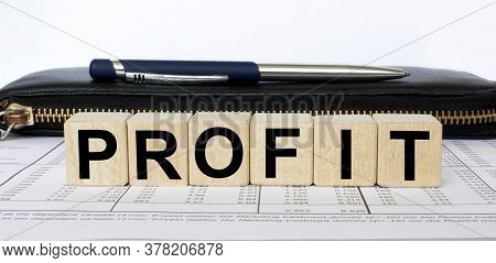 A Word Profit Written In A Wooden Cube With A Pen And Wallet