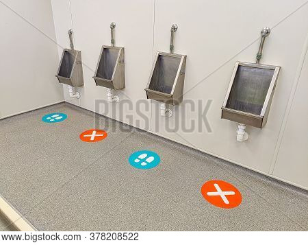 Signs On A Floor Indicating Socal Distancing In A Mens Toilet