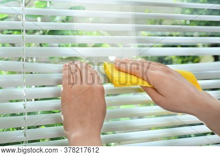 Woman Cleaning Window Blinds With Rag Indoors, Closeup