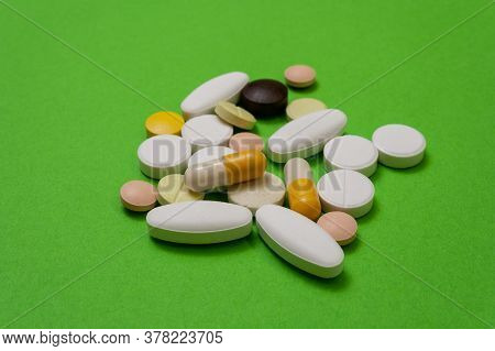 Colorful Round Pills And Capsules On A Green Background Close Up, Macroshot Tablets, Isolated. Pande