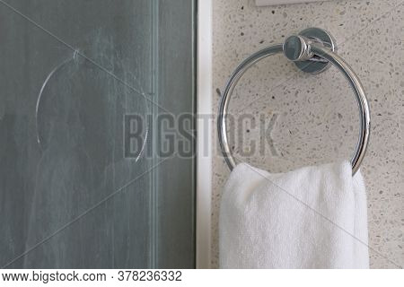 Close Up. White And Clean Towel Is Hanging On The Exposed Concrete Wall In The Bathroom.
