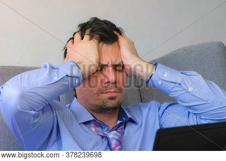 Portrait Of Tired Man Rubbing Eyes Working On Laptop Sitting On Couch At Home, Freelance, Distant Wo