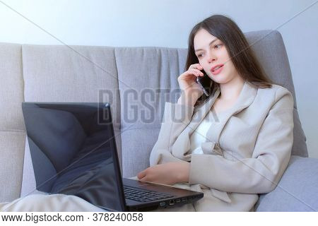 Businesswoman Working On Laptop And Talking On Smartphone At Home Sitting On Couch, Distant Work. Co