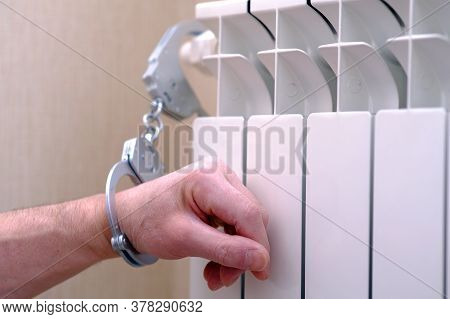 Handcuffs On The Hand. The Hand Is Handcuffed To The Radiator Of The Heater. The Concept Of Self-iso