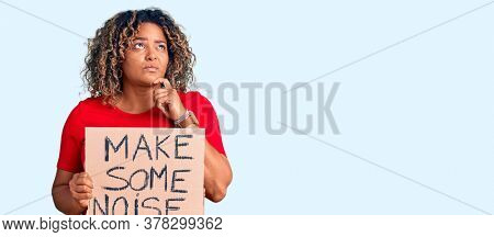Young african american plus size woman holding make some noise banner serious face thinking about question with hand on chin, thoughtful about confusing idea 