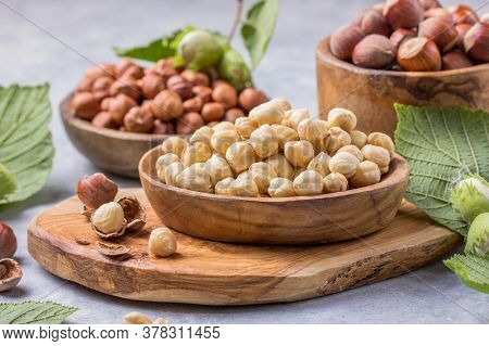 Hazelnuts With Peeled Hazelnut And Leaf  In Brown Bowl On Concrete Background. Top View Of Hazelnuts