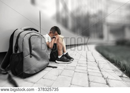 child with backpack in depression is sitting on the floor doesn't want back to school