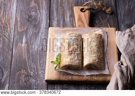 Sweet Mexican Chimichanga With Banana And Strawberries, Sprinkled With Powdered Sugar On A Wooden Ta