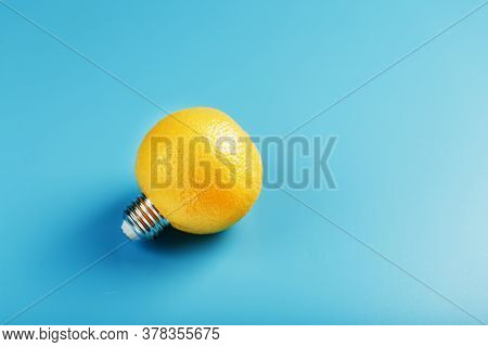 Lemon Light Bulb On A Blue Background. The Fruit Of A Lemon With Base From The Bulb E27.