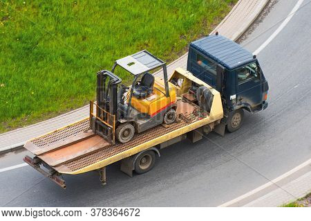 A Truck Is Transporting Loader Forklift On The Road