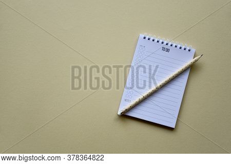 Notepad With Pencil On A Beige Paper Background. Top View. Close-up. Flat Lay.