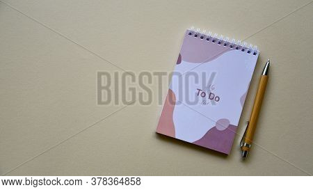 Notepad With Wooden Pen On A Beige Paper Background. Top View. Close-up. Flat Lay.