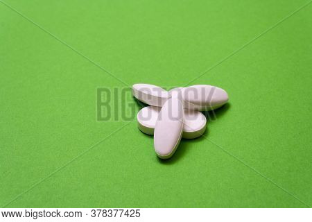 Heap White Pills, Drugs On A Green Background Close Up, Macroshot Tablets, Isolated. Pandemic Medica