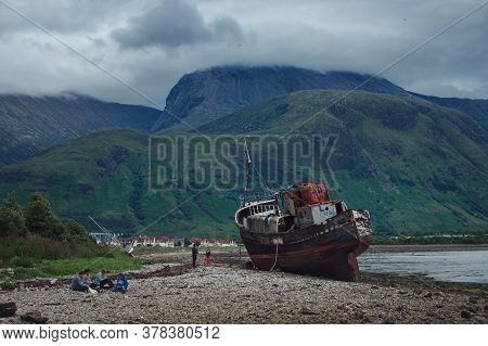July 11, 2020. People Rest On The Shore Of The Sea Bay Near An Old Ship Washed Ashore At The End Of 