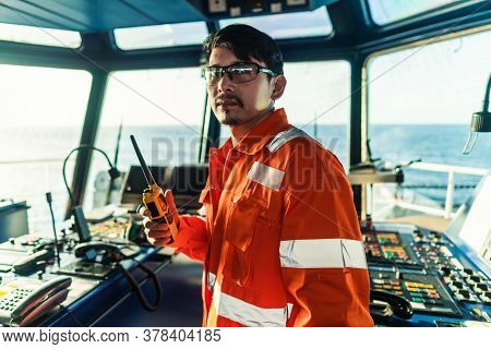 Filipino Deck Officer On Bridge Of Vessel Or Ship. He Is Speaking On Gmdss Vhf Radio
