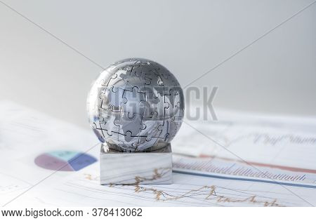 Metal Globe Resting On Paper Currency. Spherical Puzzle With A Single Piece Disconnected