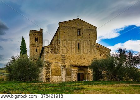 Ancient magnificent abbey of San Antimo. Autumn day. Green lawn and park around the abbey. Picturesque Tuscany. The concept of active, rural and photo tourism