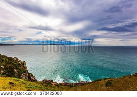 The picturesque coast of the Pacific Ocean. Sunset sky portends a storm. Nugget Point Lighthouse on the Cape Nugget. South Island, New Zealand. The concept of active, environmental and photo tourism