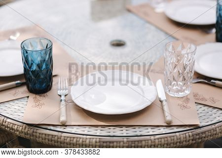 Close Up Of Served Table Set At Suumer Terrace. Cutlery In Cafe. Blue Glasses