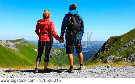 hikers couple with backpack standing on the top of mountain, enjoying mountain panorama
