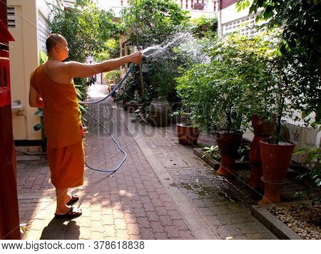 Bangkok, Thailand, February 4, 2013: Buddhist Monk Waters The Plants In A Temple In Bangkok, Thailan