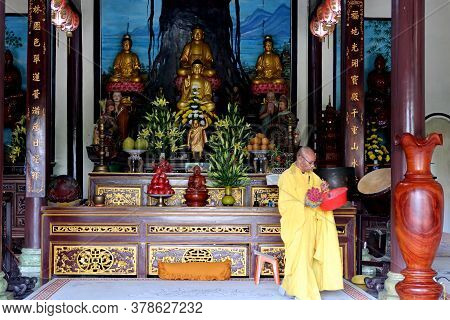 Hoi An, Vietnam, February 23, 2020: Buddhist Monk Places Flowers At A Temple In Hoi An, Vietnam.