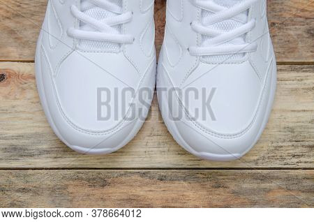 Beautiful Pair Of New White Women's Sneakers On A Wooden Background Close Up, View Top. Sock Part Of