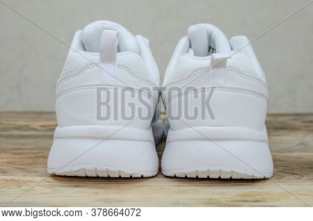 Beautiful Pair Of New White Women's Sneakers On A Wooden Background Close Up. Heel Part Of Sneakers 