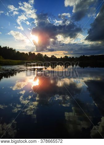 Summer Landscape: The Sky With Clouds And The Forest On The Horizon Are Reflected In The Clear Water