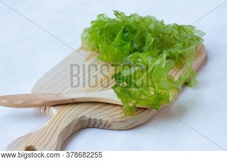 Fresh Green Leaves Of Ulva Seaweed, For Making Salad, On A Wooden Board, Light Background