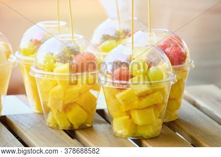 Plastic Cup With Fruits Like Pineapple And Blackberries On The Counter.